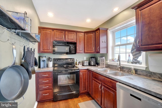 kitchen featuring sink, black appliances, and light wood-type flooring