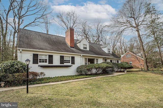 view of front facade with brick siding, a chimney, and a front yard