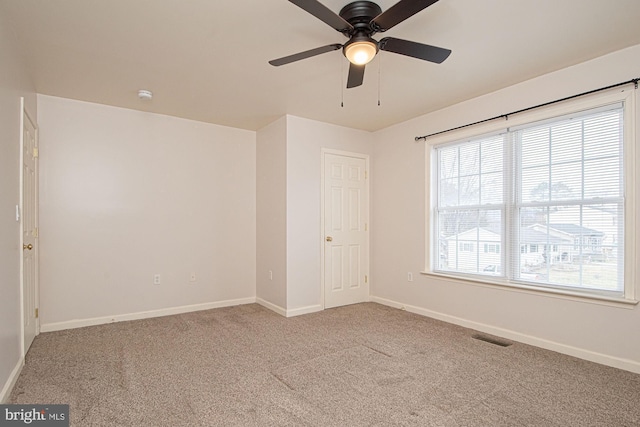 carpeted empty room with baseboards, visible vents, and ceiling fan