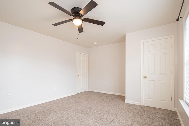 unfurnished room with a ceiling fan, light colored carpet, and baseboards