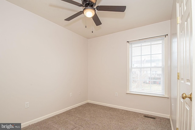 carpeted empty room featuring a ceiling fan, visible vents, and baseboards