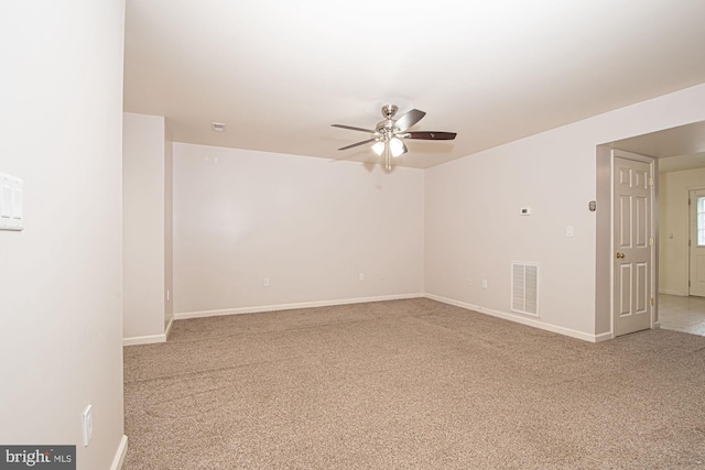 carpeted empty room featuring ceiling fan, visible vents, and baseboards