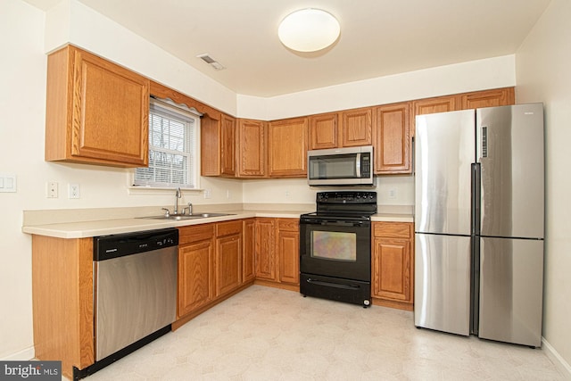 kitchen featuring appliances with stainless steel finishes, light countertops, a sink, and visible vents