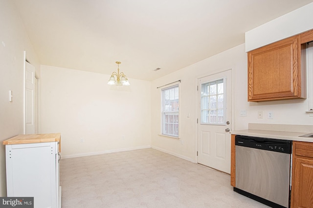 kitchen featuring brown cabinetry, light countertops, stainless steel dishwasher, light floors, and a notable chandelier