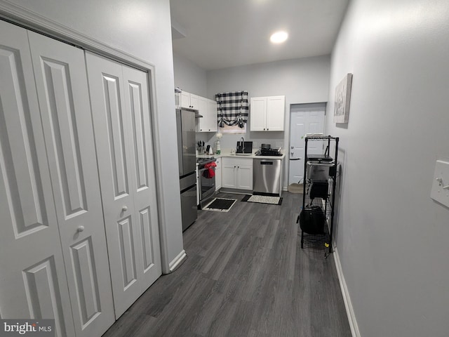 kitchen with stainless steel appliances, white cabinetry, and dark hardwood / wood-style floors