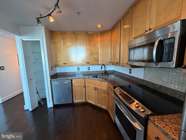 kitchen featuring dark wood-type flooring, appliances with stainless steel finishes, sink, and dark stone counters