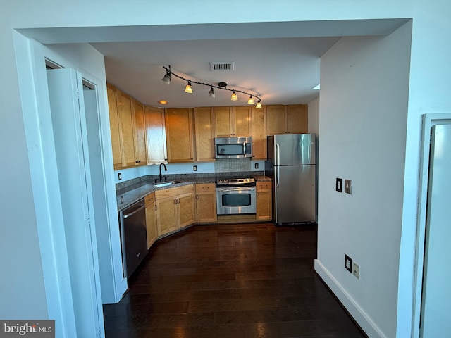 kitchen with sink, decorative backsplash, stainless steel appliances, dark wood-type flooring, and track lighting