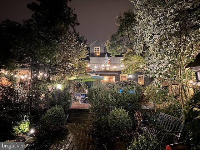 back of house at night featuring a balcony