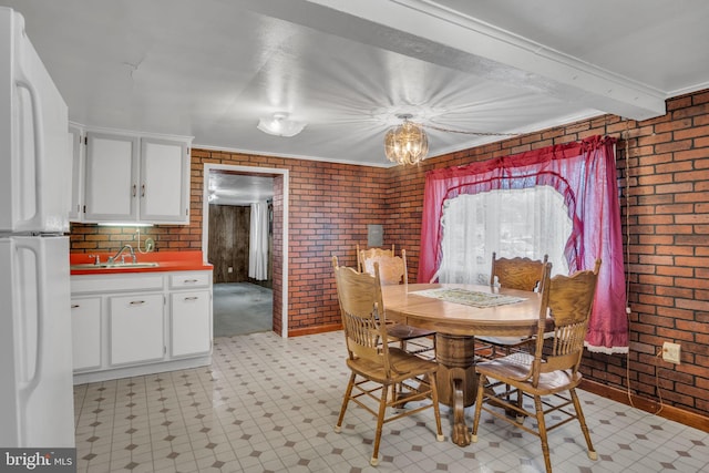 dining area featuring sink, beam ceiling, ornamental molding, and brick wall