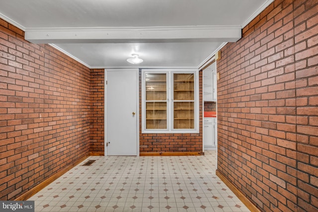 interior space featuring beamed ceiling, ornamental molding, and brick wall