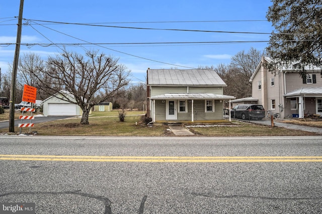 bungalow-style house with a garage, an outbuilding, covered porch, and a front lawn