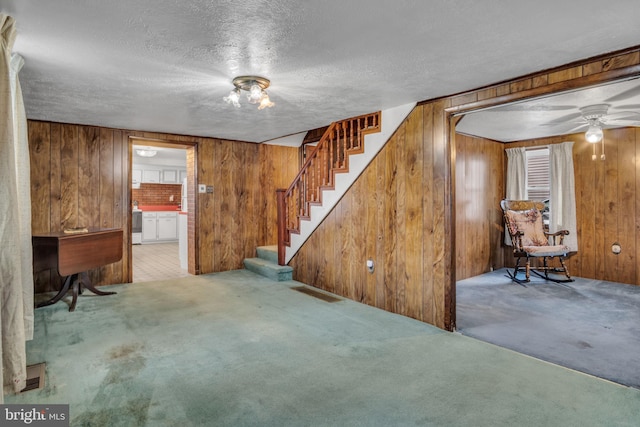 interior space with carpet flooring, a textured ceiling, and wood walls