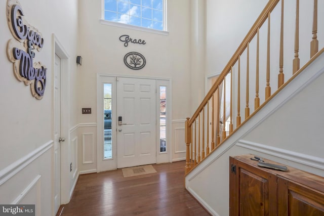 entrance foyer with a high ceiling, a wealth of natural light, and dark hardwood / wood-style flooring