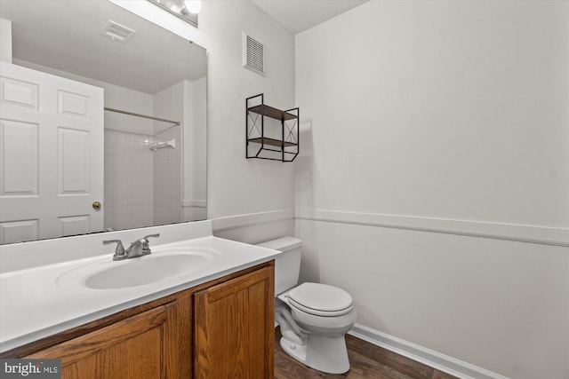 bathroom featuring vanity, tiled shower, hardwood / wood-style floors, and toilet