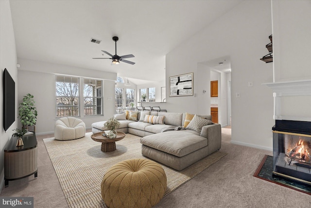 carpeted living room with high vaulted ceiling, ceiling fan, and a multi sided fireplace