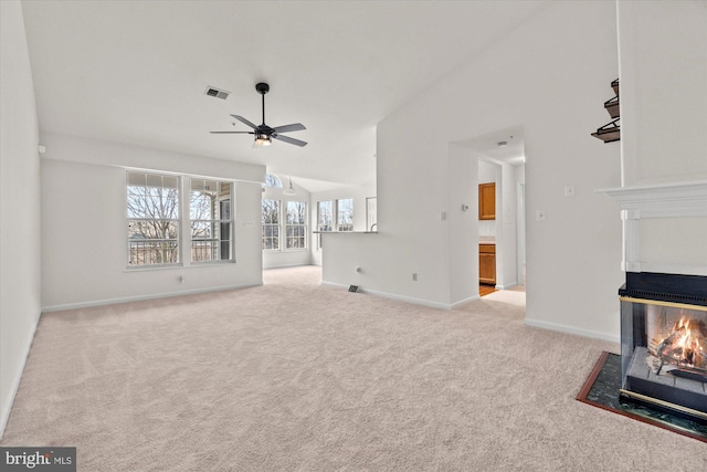 unfurnished living room with ceiling fan, a multi sided fireplace, lofted ceiling, and light colored carpet