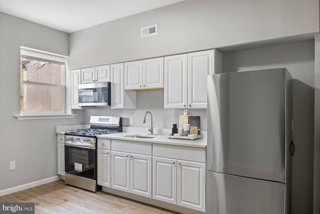 kitchen featuring white cabinetry, sink, light hardwood / wood-style flooring, and appliances with stainless steel finishes