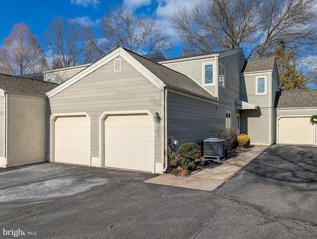 view of front of home with a garage and central air condition unit