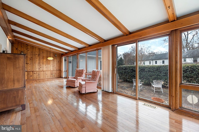 unfurnished room with lofted ceiling with beams, light hardwood / wood-style floors, and wood walls