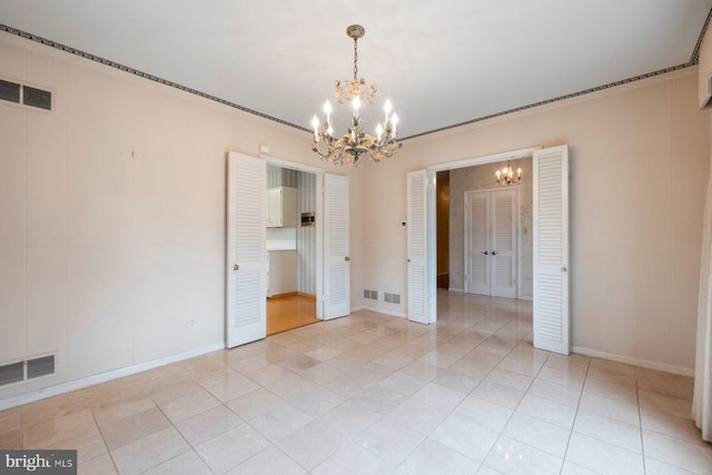 spare room with light tile patterned flooring, ornamental molding, and a notable chandelier