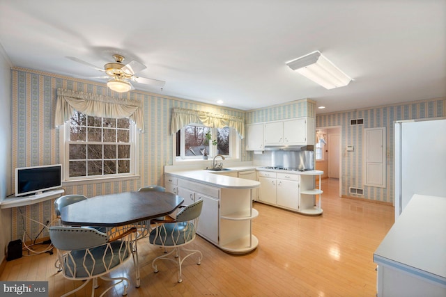 kitchen featuring stainless steel gas stovetop, white cabinetry, sink, and light hardwood / wood-style floors