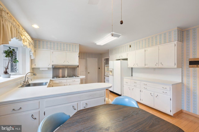 kitchen featuring sink, white cabinetry, light wood-type flooring, kitchen peninsula, and white refrigerator with ice dispenser