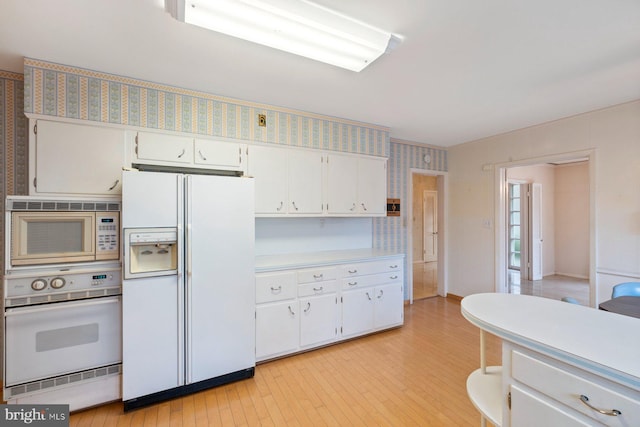 kitchen featuring white appliances, light hardwood / wood-style flooring, and white cabinets