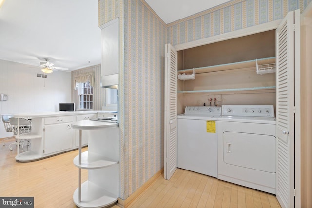 clothes washing area featuring washing machine and dryer, ceiling fan, and light hardwood / wood-style floors