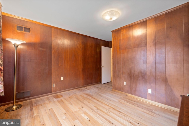 spare room featuring wood walls and light hardwood / wood-style flooring