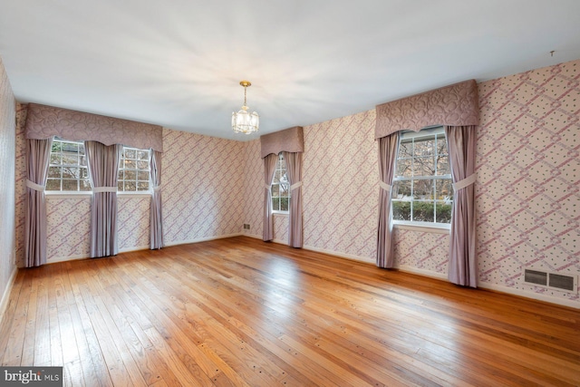 spare room with hardwood / wood-style floors and a notable chandelier