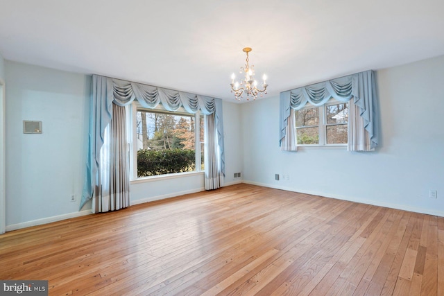 empty room with a notable chandelier and light wood-type flooring