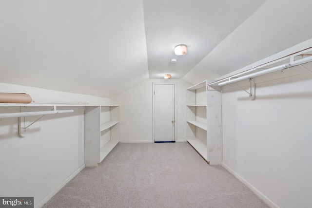 spacious closet featuring vaulted ceiling and light colored carpet