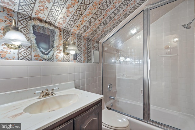 full bathroom featuring enclosed tub / shower combo, tile walls, vanity, and toilet