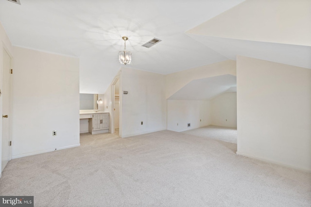 additional living space with vaulted ceiling, light colored carpet, and a notable chandelier