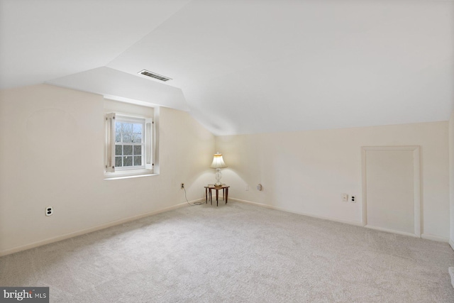 additional living space featuring lofted ceiling and light colored carpet