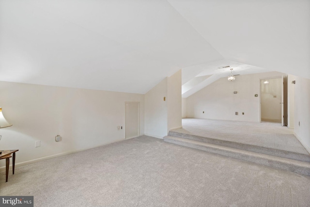 bonus room with lofted ceiling and light carpet