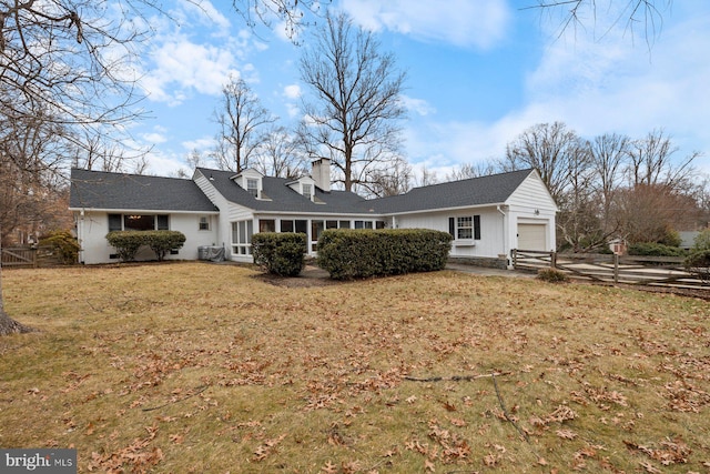 rear view of property featuring a garage and a lawn