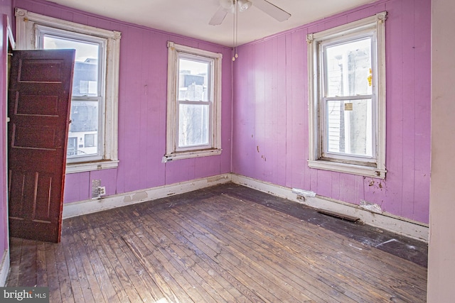 unfurnished room with a healthy amount of sunlight, dark wood-type flooring, and ceiling fan