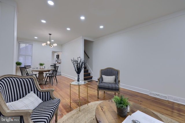 living room featuring hardwood / wood-style floors, ornamental molding, and a chandelier