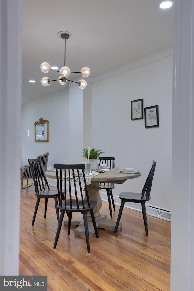 dining room featuring an inviting chandelier, ornamental molding, and light hardwood / wood-style flooring