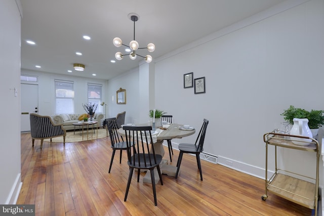 dining space with hardwood / wood-style floors and a notable chandelier