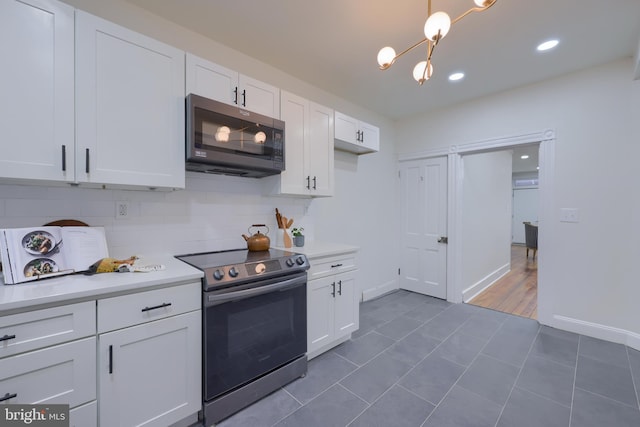 kitchen featuring decorative light fixtures, tasteful backsplash, white cabinetry, dark tile patterned flooring, and electric stove