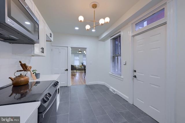 mudroom with dark tile patterned flooring and a notable chandelier