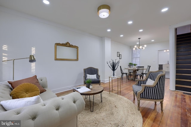 living room with an inviting chandelier, ornamental molding, and wood-type flooring