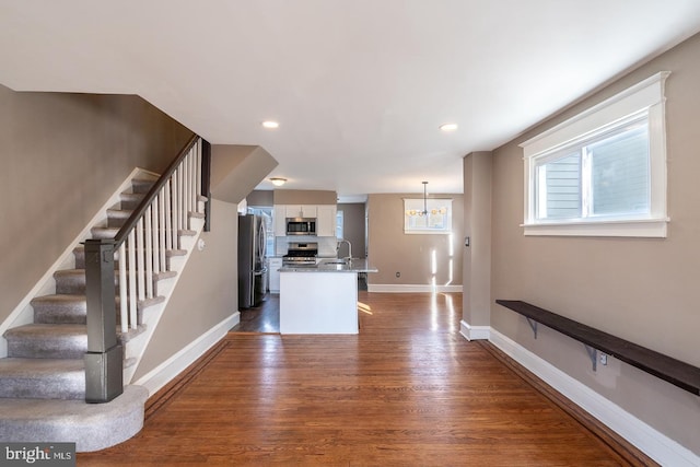 kitchen with appliances with stainless steel finishes, sink, a breakfast bar area, white cabinets, and dark wood-type flooring