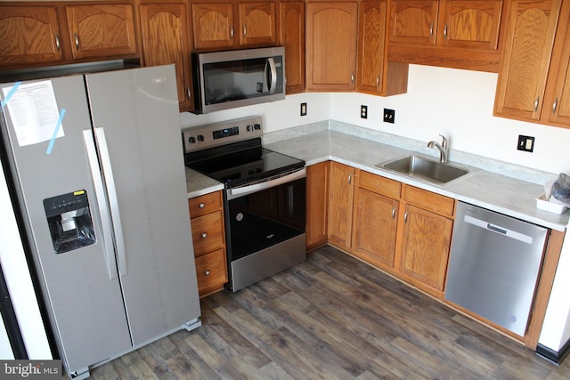 kitchen with stainless steel appliances, brown cabinetry, light countertops, and a sink