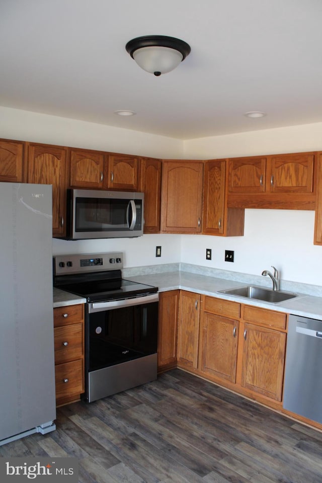 kitchen with brown cabinets, appliances with stainless steel finishes, light countertops, and a sink