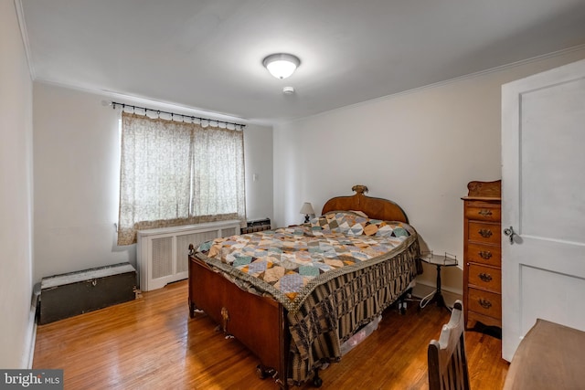 bedroom featuring ornamental molding, radiator, and hardwood / wood-style floors