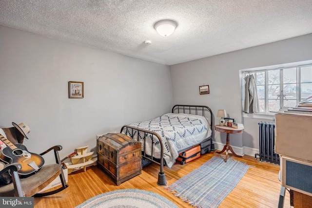 bedroom with radiator, a textured ceiling, and light wood-type flooring