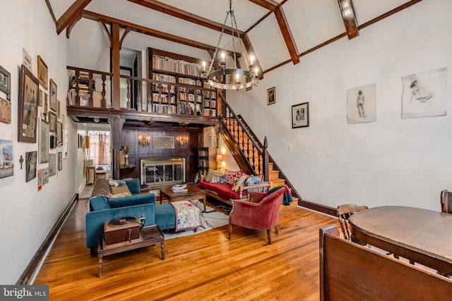 living room with a notable chandelier, hardwood / wood-style floors, beamed ceiling, and a high ceiling